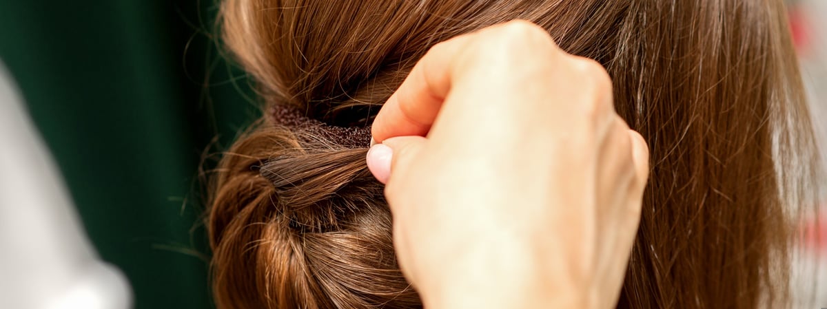 Stylist forming a French twist updo, hands working the hair
