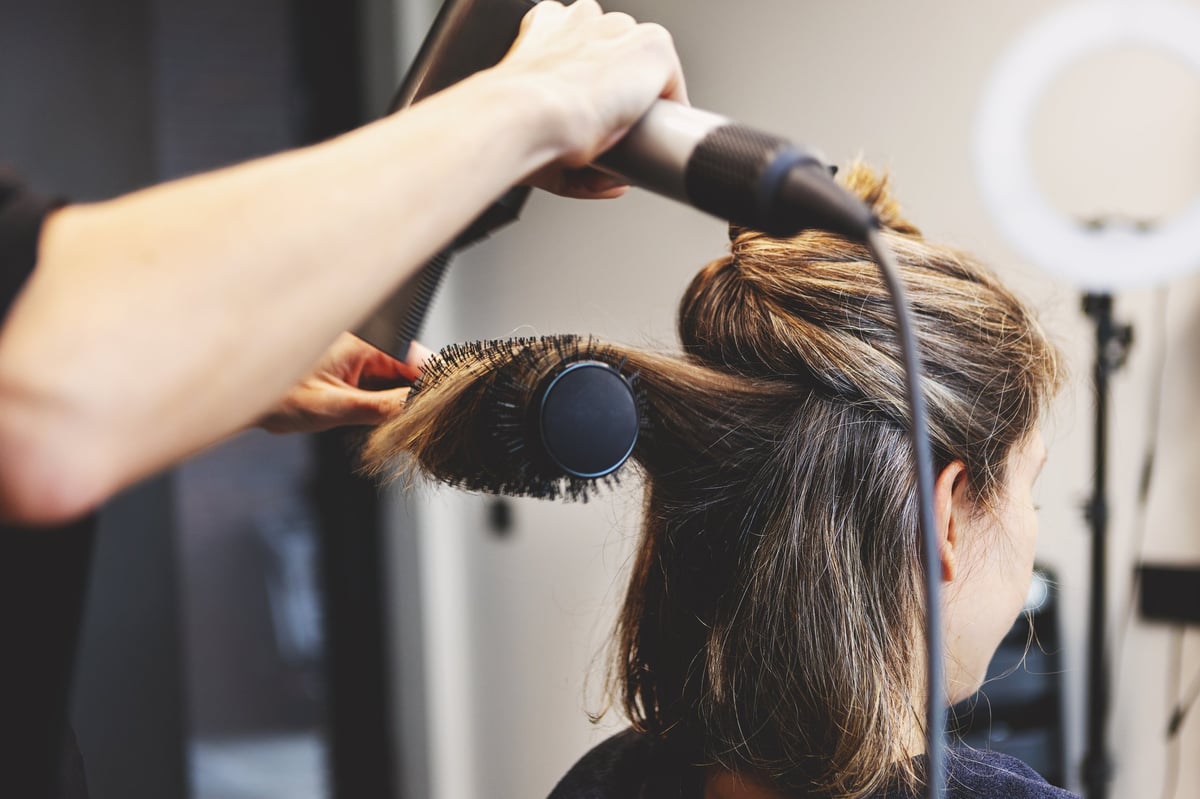 Round brush blow-dry styling sectioned strands in the salon chair